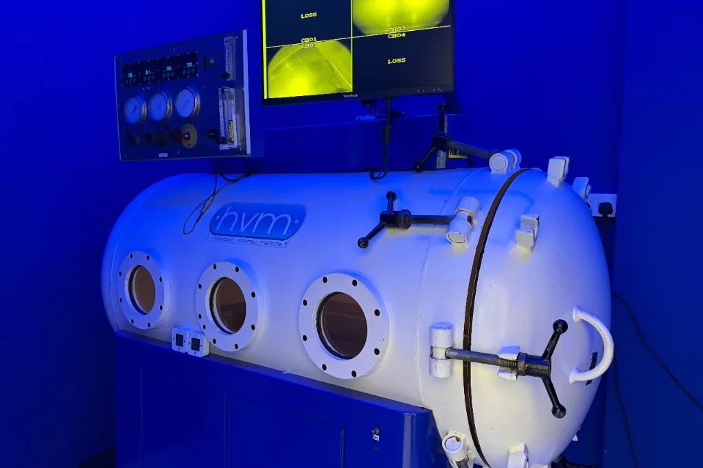 Hyperbaric oxygen treatment room with acrylic chamber and sage green walls