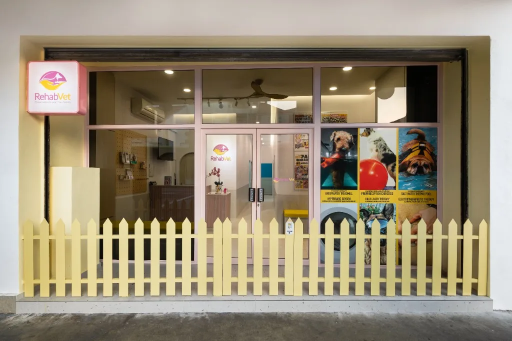 RehabVet storefront — yellow picket fence, pink sign, glass frontage
