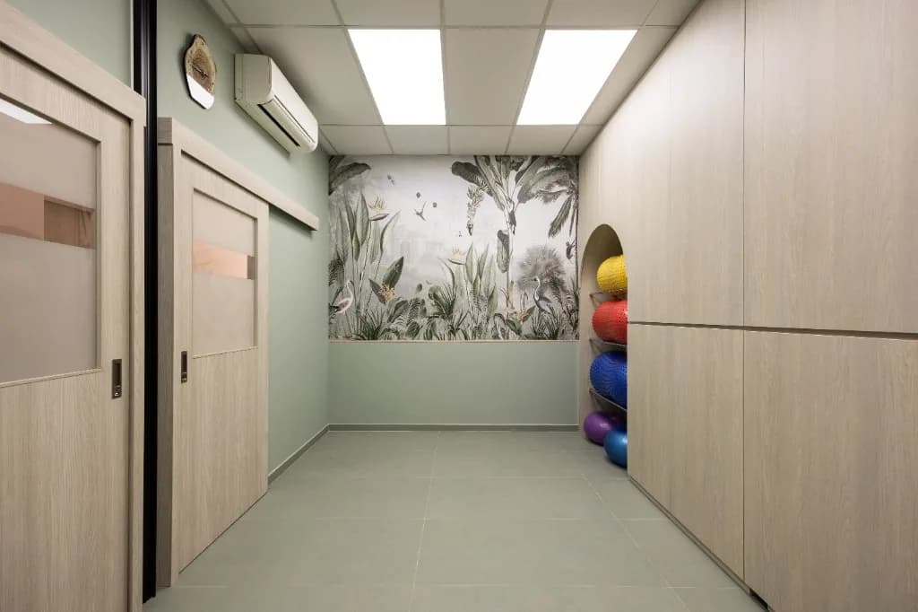 Treatment room with sage green walls, botanical mural, and exercise balls