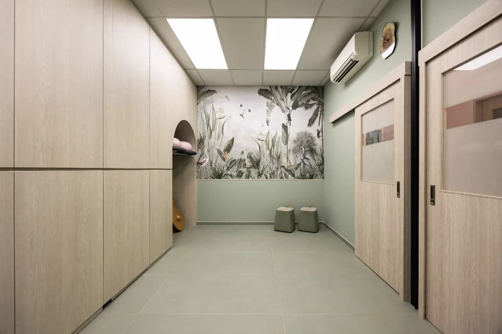 Treatment room with botanical mural, different angle, green stools
